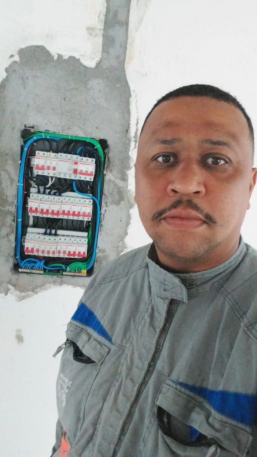 Washington, eletricista responsável pela WTR Elétrica, ao lado de quadro elétrico executado